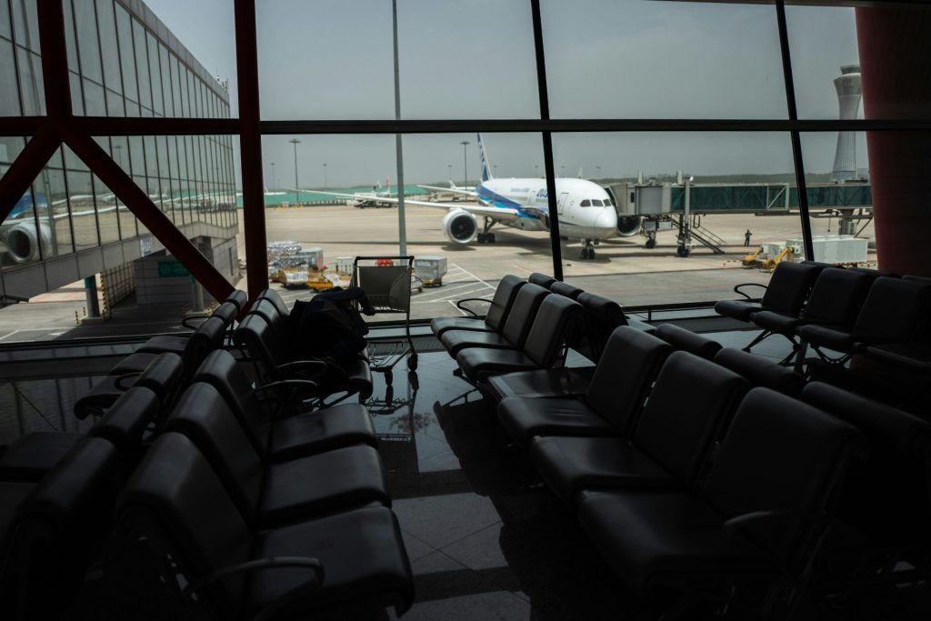 an airport terminal with chairs and a plane in the background
